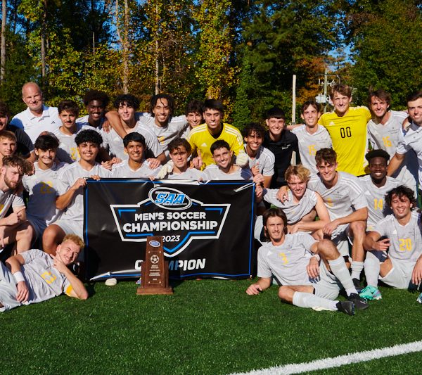 Oglethorpe University Men's Soccer Team and coaching staff pose for a photo with the SAA Conference tournament championship trophy.