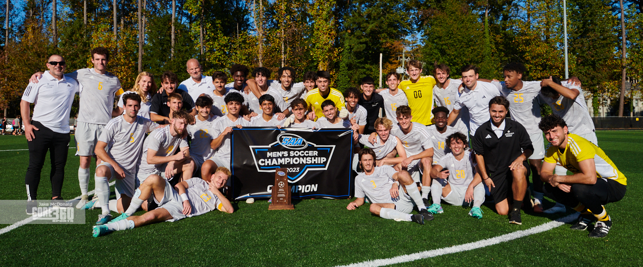 Oglethorpe University Men's Soccer Team and coaching staff pose for a photo with the SAA Conference tournament championship trophy.